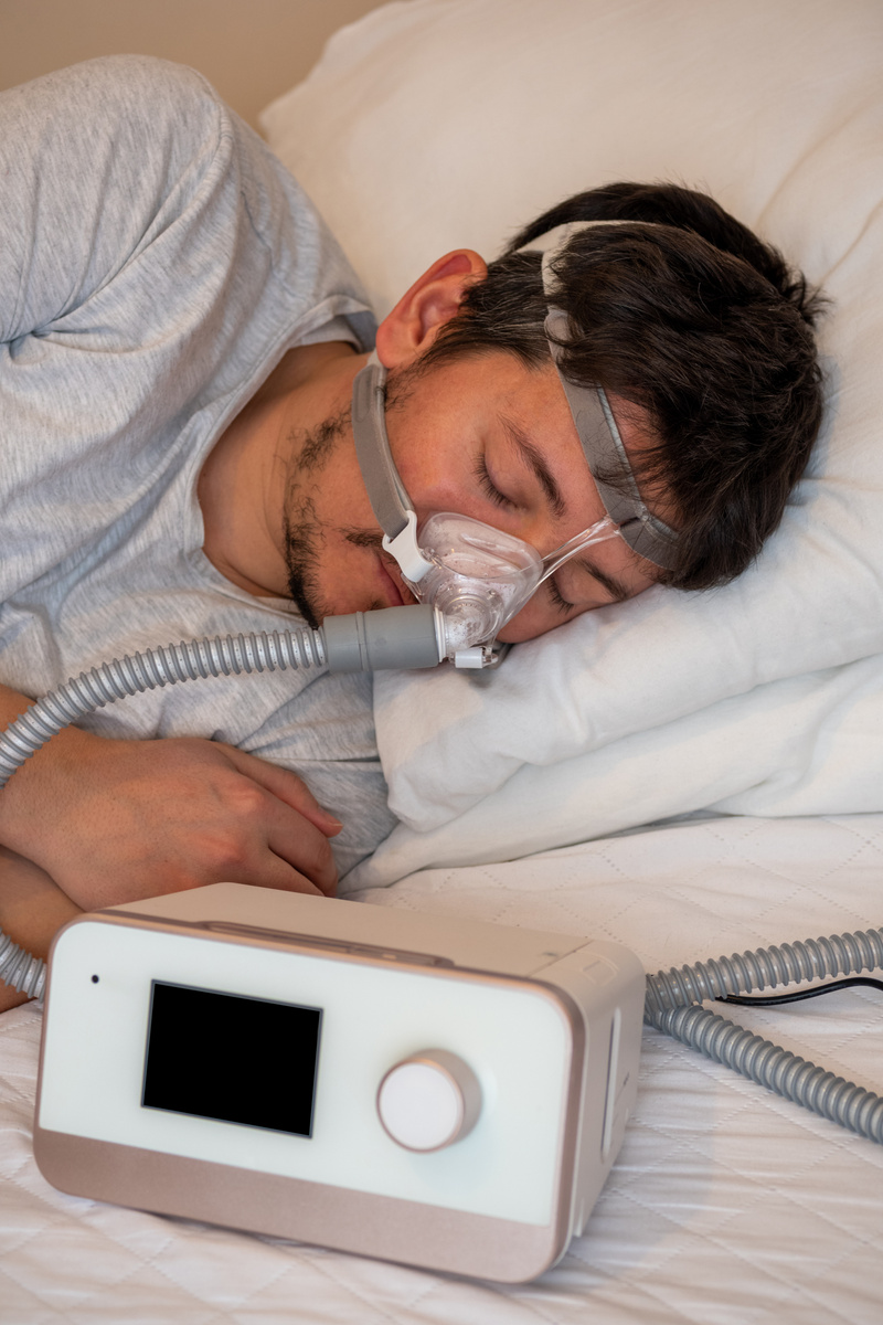 young man wearing ( CPAP Mask ) nasal mask and using CPAP machine